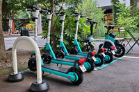 ポートと呼ばれる専用発着所に停車中の、LUUPのシェア用車両。写真奥の1台が電動アシスト自転車で、手前4台が電動キックボードだ。料金は両モデル共通で、1回の乗車あたり「基本料50円+1分ごとに15円」。ほかに「月額980円+30分利用ごとに200円」というサブスクリプションのプランも用意されている。