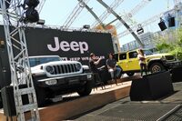 お笑い芸人の藤田憲右さんと、ステランティス ジャパンの新海宏樹氏によるトークショーの様子。背後にあるイエローの車両は、10台の限定モデル「アンリミテッド ルビコン ハイベロシティー」だ。