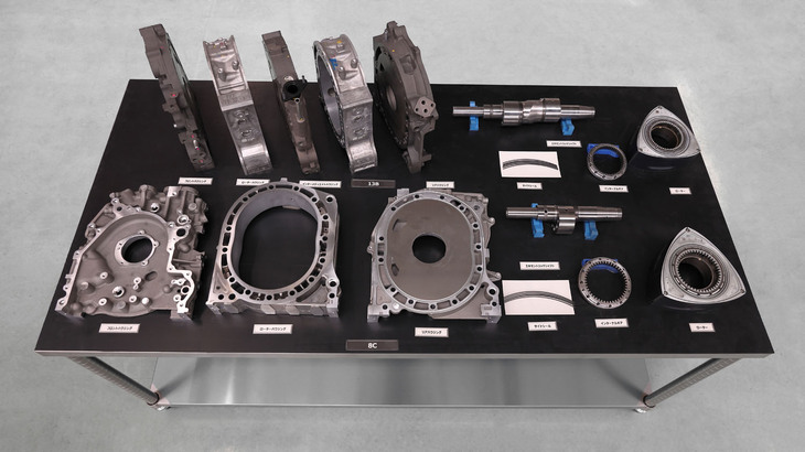 写真上が2ローターの「13B」型ロータリーエンジン、写真下が1ローターの新しい「8C」型ロータリーエンジンの構成パーツ。
