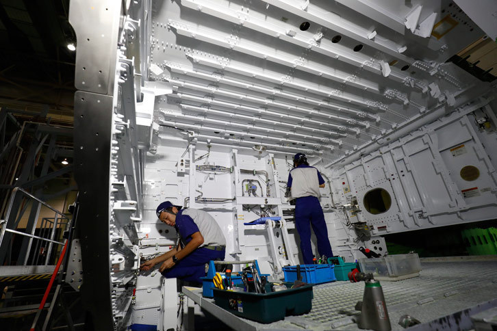 「787」の中央翼に艤装(ぎそう)を施す工程の様子。自動車の製造工程と比べて人の手による作業が非常に多い。