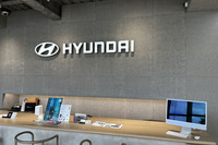 「ヒョンデカスタマーエクスペリエンスセンター横浜」の受付カウンター。グレーで統一された壁には、木毛セメント板などの再生可能素材が使用されている。各種サービスを行うだけではなく、ヒョンデが目指すクリーンモビリティーやサステイナブルという世界観を伝える役割も担うという。