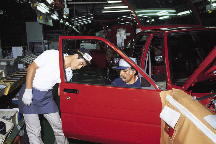 トヨタはゼネラルモーターズと合弁会社NUMMIを立ち上げ、アメリカでの現地生産を行うことを決めた。写真は日本の高岡工場にて実習を受けるNUMMIの研修生(1984年)。