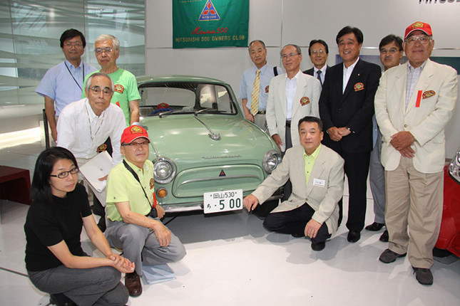 1962年「三菱500スーパーデラックス」を囲んで、オーナーである「三菱500オーナーズクラブ」会長の片山章一氏(車両右側にしゃがんでいる人物)、益子修三菱自動車社長(その後方の紺スーツ姿)、そしてクラブメンバーのみなさん。
