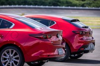 手前が「セダン」、奥が「ファストバック」。同じデザインテイストのリアコンビネーションライトが採用されているが、リアフェンダーのデザイン処理を含め、ボディー後端の印象は大きく異なっている。マツダブランドを示すエンブレムは立体的な形状で、手動のトランク(ハッチゲート)オープナーも兼ねている。