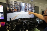 シミュレーターによる「Interactive Reality in Motion」の体験シーン。ドライバーは指さし動作により、運転しながら周囲の街や店、人などとインタラクション(相互作用)できるようになる。