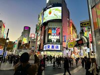 渋谷で。外国人観光客とみられる人々が、ネオンにスマートフォンのレンズを向けていた。