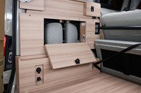 「NV200バネットMYROOM」の車内後方側面には、収納スペースのほか、車外からの給電コネクターや、コンセント、照明・空調のスイッチなどが備わる。写真は「2 in 1シート」のヘッドレストをおさめた状態。