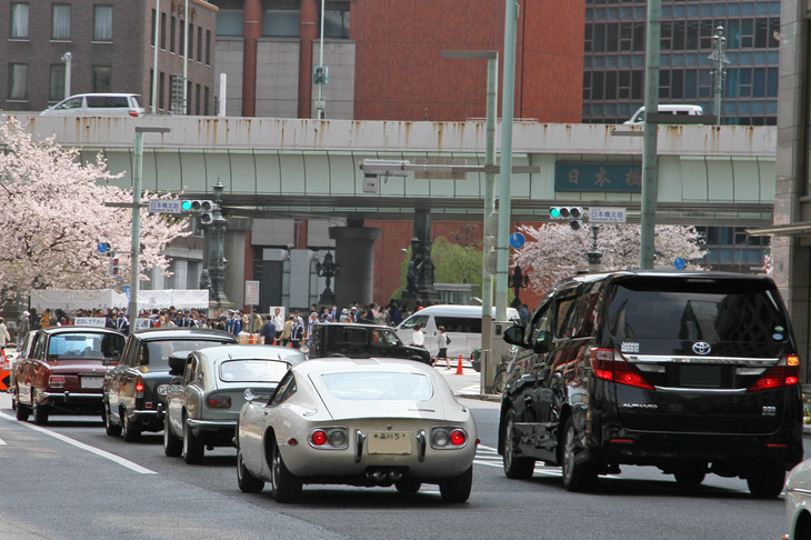 先の「いすゞ・ベレット」や「ローバー2000SC」に1967年「ホンダS800クーペ」や1967年「トヨタ2000GT」が続く。並走する「トヨタ・アルファード」が大きく見えること!