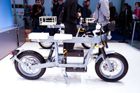 スウェーデンの電動バイクブランド「CAKE」。MTBのようなモトクロスバイク「Kalk(カーク)」シリーズで話題となった彼らの新作がこれ。「Ösa(オーサ)」はKalkとは異なるコミューターで、フレームを兼ねた車体中央を貫く鉄棒に、専用クランプであらゆるアイテムをセットし、ユーザーの用途によって形を変えられるという。奥にあるのは高出力タイプで、サスペンションやブレーキシステムも異なる。