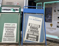 新聞雑誌スタンドでは通常営業が行われている。店外の見出しには、定年退職した医師が呼び戻されていること、行動制限に違反した人物が初めて検挙されたこと、開店している商業施設の一覧などが記されている。