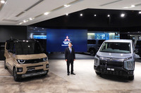 三菱の加藤社長と、写真右が「デリカD:5」、同左が「デリカミニ」。