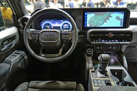 外観同様、直線基調のデザインが採用された「ランドクルーザー“250”」の運転席周辺部(写真は左ハンドルの海外仕様車)。センターコンソールには、シフトレバーやパーキングブレーキスイッチのほか、走行モードおよび4WDシステムの切り替えスイッチが並ぶ。