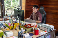 ワーキングスペースでPCに向かう神戸アレック氏。「短パンで作業することも多いので、蒸れたりこもったりするのは困ります。でも、実際には粉を塗っているのかと思ってしまうほどすべすべで、感動的でした」と、「エピック メルセデスAMGペトロナスF1チーム 2021エディション」のハイブリッドPUレザー表皮を絶賛した。