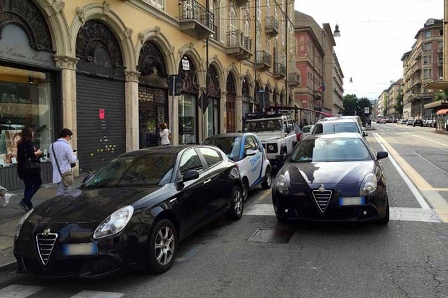トリノ名物(?)の二重駐車。くしくも「アルファ・ロメオ・ジュリエッタ」が先頭に並ぶ。奥のカーシェアリング用「スマート」が脱出できるか心配になる。