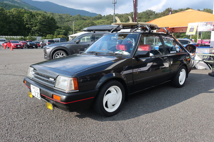 出展者ブースで発見した5代目「ファミリア」。当時流行した「陸（おか）サーファー」仕様となっているのもポイント。ヘッドレストのバンダナや白いフィンタイプのアルミホイールなどでドレスアップが施され、まるで80年代からタイムスリップしてきたかのようだ。