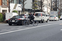 2026年1月中旬、東京・渋谷区の某所にて、ビュンビュンとクルマが行き交う大通りを平然と斜め横断する自転車。「いざとなったらクルマの側が止まってくれる」と考えているのかもしれないが……。