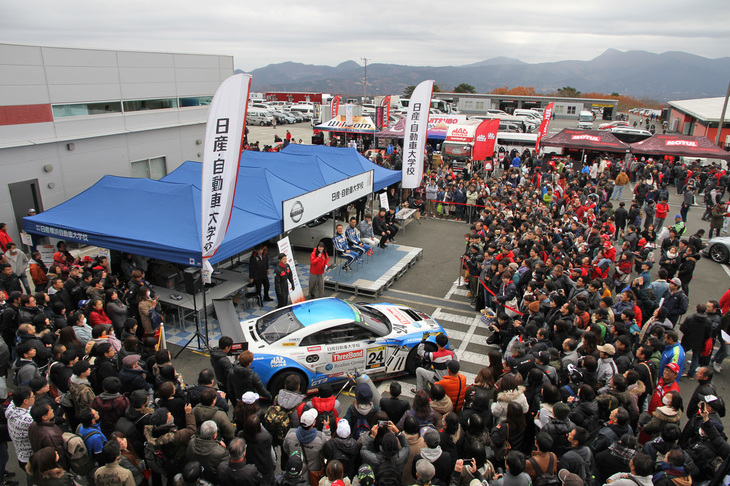 パドックにはタイヤやオイルメーカー、チューナーやショップなどのブースが所狭しと並び、いずこも大盛況。中でもひときわたくさんのギャラリーを集めていたのは、KONDO Racingとのコラボレーションでスーパー耐久に参戦している日産自動車大学校。これは近藤真彦監督とドライバー、スタッフによるトークショーに続いて、学生によるピットワークシミュレーション（タイヤ交換）が行われているところ。