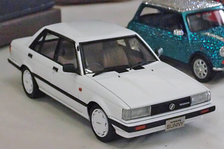 “トラッド・サニー”のキットなんてあったのか!? と思いつつ解説プレートを見たところ、なんとベースはアオシマ製1/24「トヨタ・カローラセダン（KE70）」。それをライバルであるサニーに変身させてしまったのだ。