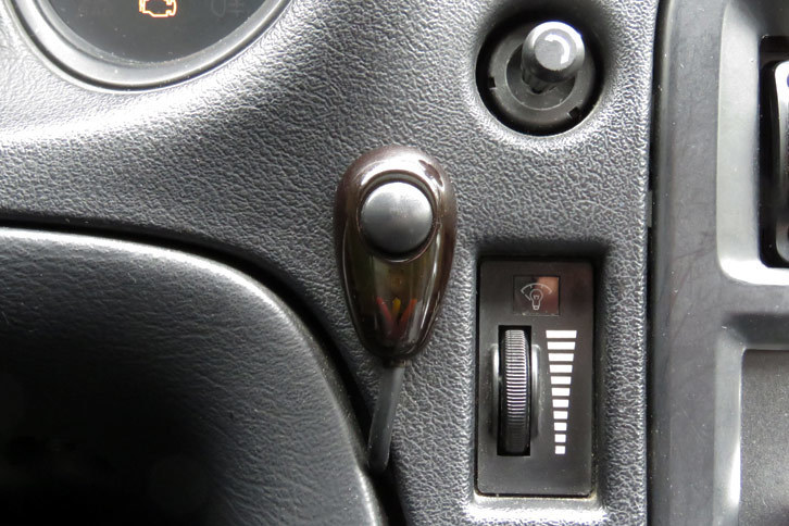 （証拠写真A）ダッシュボードに貼り付けられた、ナゾのスイッチ。周辺とは明らかに質感が違う。何というか、台所などで見かけるあの生命体を思わせる色とツヤをしている。