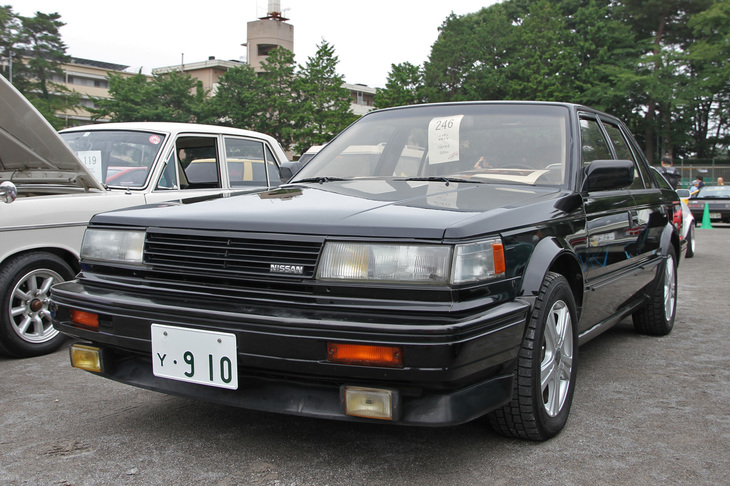 1987年「日産マキシマ」。日本国内では「ブルーバード マキシマ」として販売された、7代目ブルーバード（U11）のV6エンジン搭載車の北米仕様。国内向けにはない3リッターエンジン（VG30E）を搭載している。マニアが中古を個人輸入したのかと思ったら、新車当時に正規ディーラーの東京日産が20台輸入したうちの1台とのこと。そんな事実があったことを初めて知ったが、オーナーによれば、東京日産はこれを国内仕様の2倍以上の約500万円で売ろうとしたというから驚く。バブル時代ならではの話である。駐留米軍人／軍属用のYナンバーはイベント展示用のダミー。