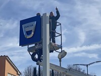 外ではダチアの旧看板の取り外しが行われていた。レンズを向けると、作業員のおじさんが応えてくれた。