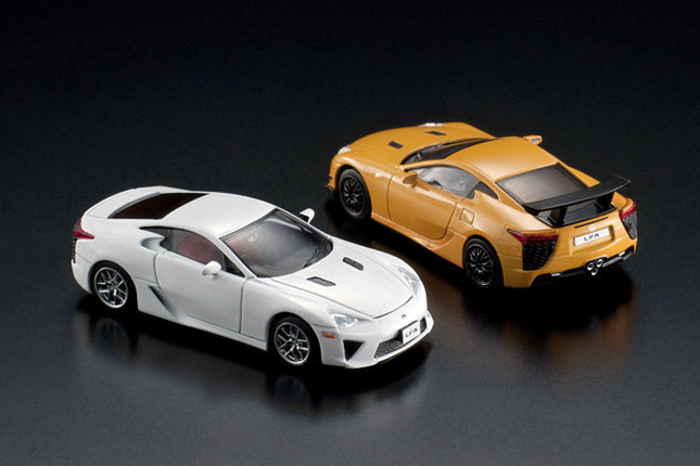 今回、書店で販売される「レクサスLFA」のミニチュア（写真手前）。オレンジ色の個体「LFAニュルブルクリンク・パッケージ」は、ネット通販で扱われる。