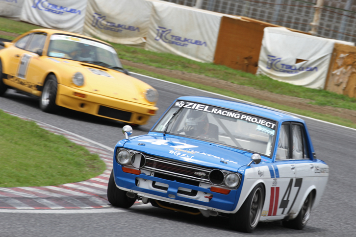 S68/75レースで2位争いする、BREカラーをまとった予選2位の1970年「ダットサン・ブルーバード1800SSS（H510）」と予選3位の1975年「ポルシェ911カレラ3.0」。最終結果は911が2位、H510が3位。