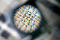 チェック柄の織物生地をルーペで拡大して見たところ。ブルーやオレンジの糸が織り込まれているのがわかる。