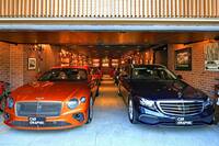 木製の大きなはね上げ式のシャッターを開けると、6台のクルマたちが迎えてくれる。ガレージは間口に対して奥行きがある。扉の上に見える住宅の外壁の縦格子がすてき。