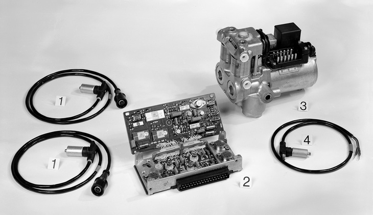 ダイムラー・ベンツとボッシュが共同開発した、世界初となる電子制御ABSの構成部品。（1）が前輪用の速度センサー、（2）がコントロールユニット、（3）が油圧ユニット、（4）がリアアクスルのドライブピニオンに備わる速度センサーである。