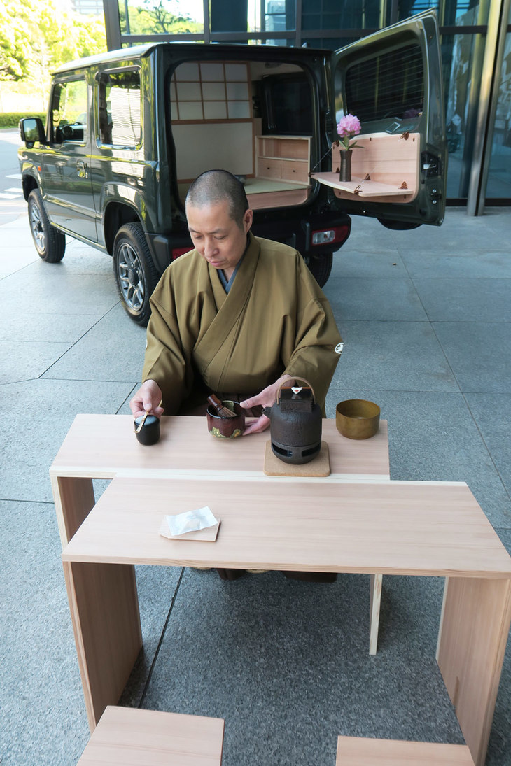 「ジムニー」に合わせてあつらえられたテーブルセットでお茶をたてる、京釜師の三代目吉羽與兵衛さん。伝統工芸を軸にしたキワコトのビスポークは、既存のそれとは一線を画す趣をただよわせていた。