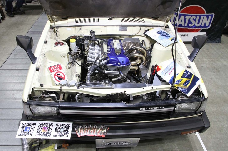 DOHCエンジンにスワップされた4代目「トヨタ・カローラ バン」。トヨタの4A-Gかと思いきや、どうも見た目が違う。なんと先代「スズキ・スイフトスポーツ」用のM16Aを縦置きし、「ジムニー」用の5段MTと組み合わせているという。タコ足はワンオフ。