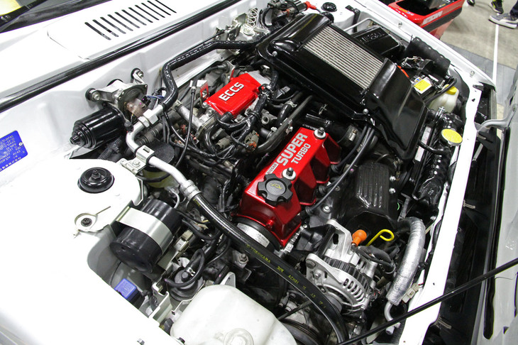 「日産マーチR」のツインチャージドユニット。過給係数1.7をかけて1600cc以下のクラスに収まるようノーマルの987ccから930ccに縮小した直4 SOHCエンジンに複合過給機を備えて最高出力110PS、最大トルク13.3kgf·mを発生する。