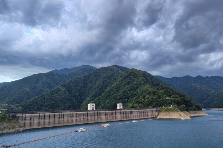 小河内ダムの堤と雨雲を、奥多摩湖畔から眺めるの図。今夏の渇水を思えば慈雨なのでしょうが、なにも今日降らんでも……。