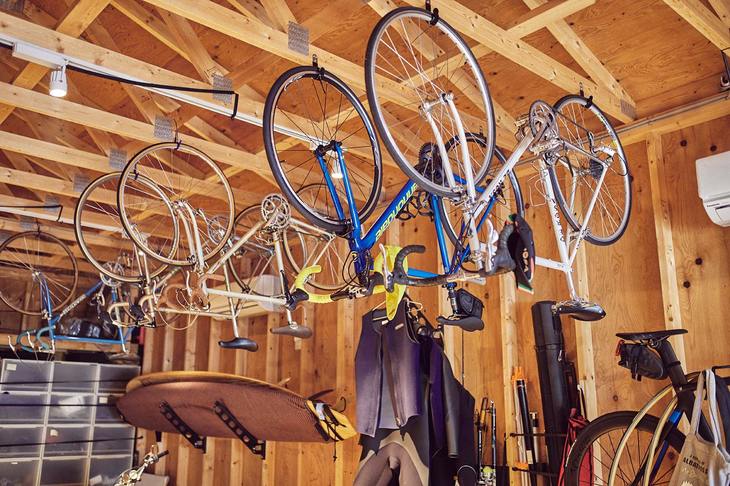 物の収納に梁（はり）や柱を利用できるのは木造ならではだ。ロードバイクはこうしてつるされている。よく見ればサーフボードもある。入川氏は多趣味なので、それぞれの趣味に応じたギアはバラエティーに富む。