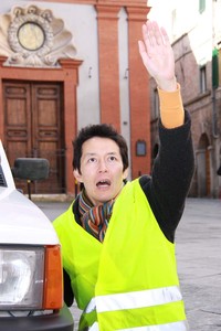 路肩で救援を求める筆者（模擬）。黄色いベストは高品質なものでなければ、日本円にして400円程度が相場である。