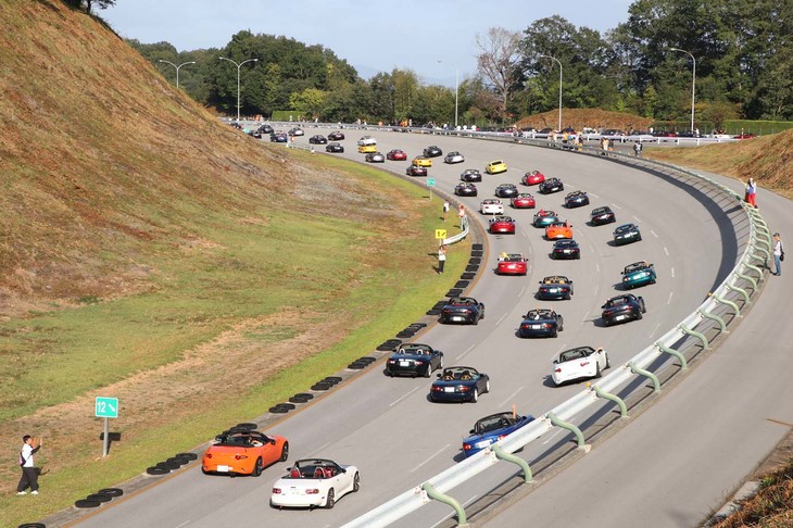 三次自動車試験場の高速外周路をパレードするのは、2000台のロードスター。手を振る白いシャツの人たちは、イベントをサポートしたマツダ社員の方々だ。周回を終えたロードスターから帰路につく。最後の1台が退場するまで2時間以上かかったそうだ。