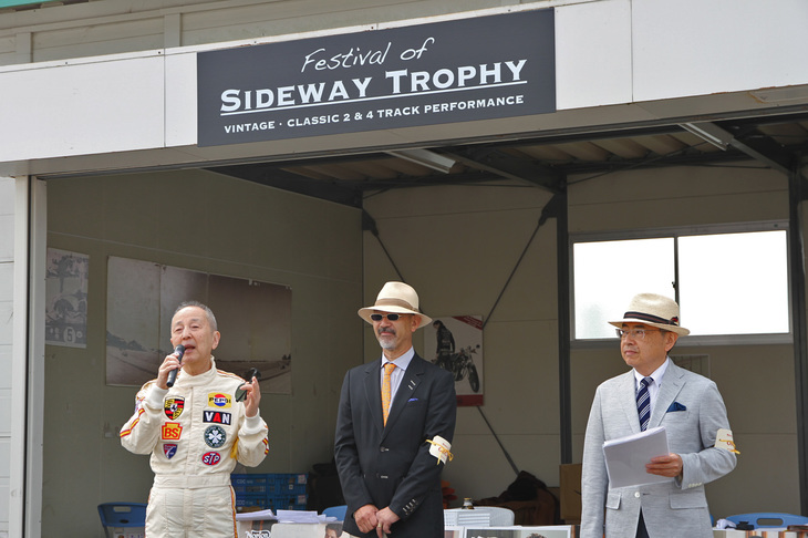 開会式にて、左からレジェンドドライバーにして、イベントの名誉プレゼンターを務める生沢 徹さん、イベントを主宰する英国車専門店パルクフェルメ代表の金子 温さん、そして進行役を務めるモータースポーツジャーナリスト／レースアナウンサーの中島秀之さん。