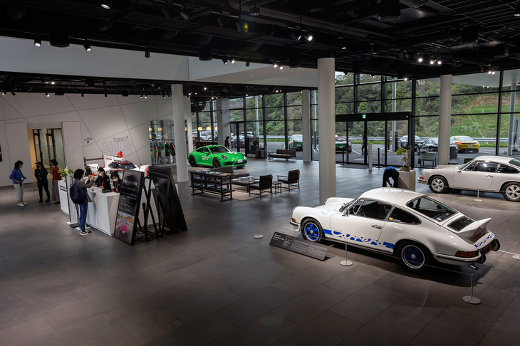 メインビルディングに入ると、歴史的なミュージアムカーなどが展示されたアトリウムが広がっています。同じフロアには限定商品などを販売するオフィシャルアイテムショップや「956カフェ」が、2階には「レストラン906」やラウンジ、ミーティングルームのほか、世界有数のレーストラックをさまざまな車両で走行できるシミュレーター・ラボなどもあります。