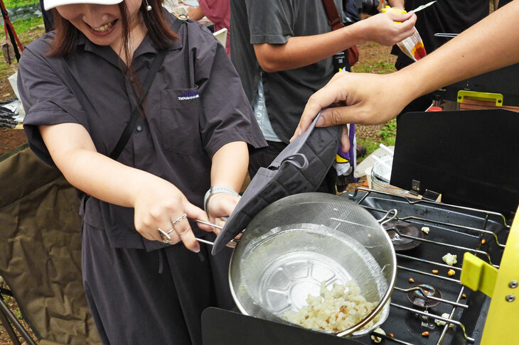 アルミの“フライパンもどき”に油を敷いて、コーンを投入！ はじけるコーンをザルでガードするのだが、その際には油もはねるので、恐いやら熱いやら。