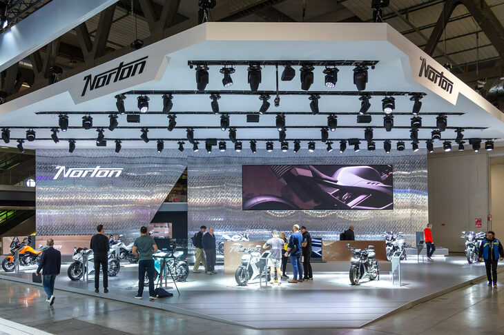 「EICMA 2025」の会場より、ノートン・モーターサイクルズのブースの様子。モダンな書体の、新しい「Norton」のロゴが掲げられている。
