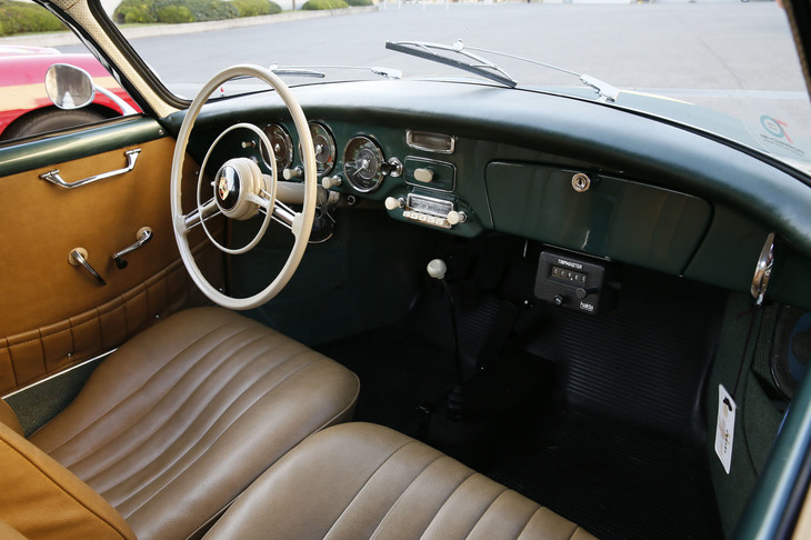 外装色に合わせたグリーンのインストゥルメントパネルにブラウンのシートやドアパネルが組み合わされた「356A 1600クーペ」のインテリア。ステアリングホイールやスイッチ類、シフトレバーはアイボリー色でコーディネートされている。