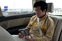 アルファードのサードシートに座り、タイヤの違いによる、オーディオ音の聞き比べをするリポーター。