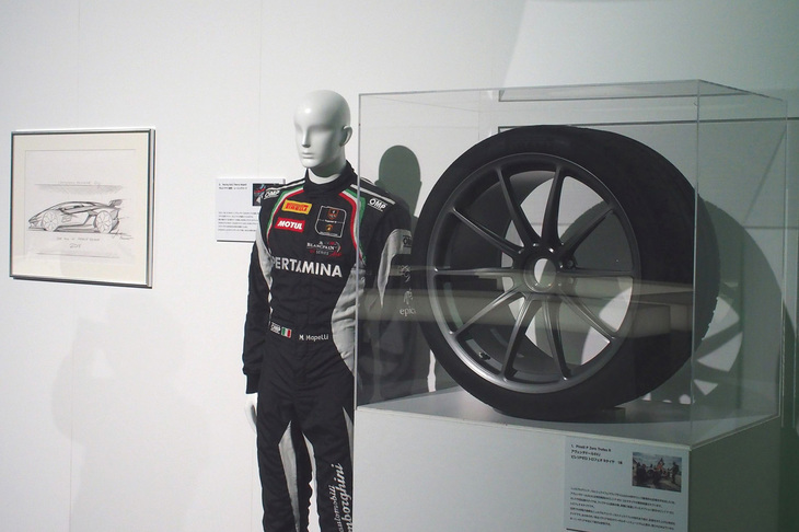 ニュルブルクリンク北コースでベストラップを更新した際にドライバーのマルコ・マベリ氏が着用していたレーシングスーツと、実際に装着されていたオプション設定のタイヤ「ピレリPゼロ トロフェオR」。奥に見えるのは、ランボルギーニのデザイナー、ミィティア・ボルケルト氏が描いた世界でただ1枚の「アヴェンタドールSVJ 63」のデザインスケッチ。これらの品は同日夜のパーティーでチャリティーオークションにかけられ、その収益は北海道および大阪の災害復興のため寄付された。