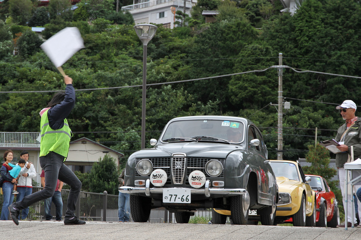 パイロンスラロームでスタートする1968年「サーブ96モンテカルロV4」。基準タイム（51秒）にいかに近く走れるかを競うパイロンスラロームには31台が参加した。スピード競技ではないのでヘルメット着用義務はなく、同乗者（ナビゲーター）もOK。