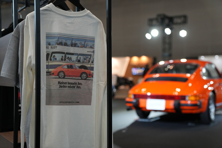 会場では、ポルシェライフスタイルの新製品として「レトロコレクション」も発表された。写真はクラシックな趣のロングスリーブシャツと、そのイラストと“おそろい”となる、オレンジの「ポルシェ911」（1976年）。