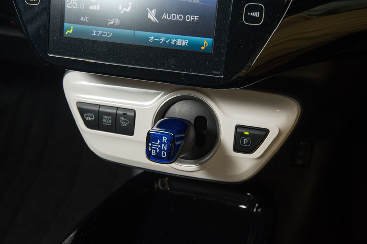 シフトセレクター（写真中央の青いレバー）の周辺には、走行モード切り替えなどの各種スイッチが備わる。一番左は「HV／EV切り替えスイッチ」で、長押しすると、ハイブリッド走行と充電を同時に行う「バッテリーチャージモード」を選択できる。