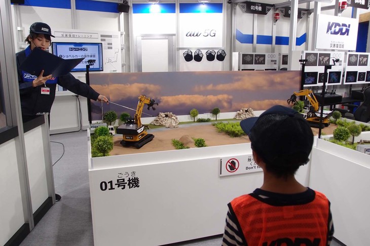こちらはKDDIのコーナー。新しい5G通信の環境における、災害復旧の仕事に取り組む。具体的には、ラジコンのショベルカーを遠隔操作し、復旧作業に従事する。