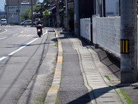 仮に歩道が設置されていても、クルマの出入りのために数mおきに削られて、このように波打っている。しかもその半分は地下排水口のふただから、ひどく歩きにくい。手押しクルマで歩く老人は本当に苦労していた。