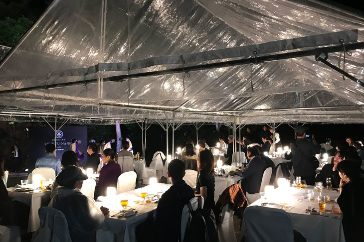 ディナー開始と同時に降ってきた雨により、急きょテントを立てての開催となった。天候の変化を楽しみながらのディナーもダイニングアウトの醍醐味（だいごみ）。